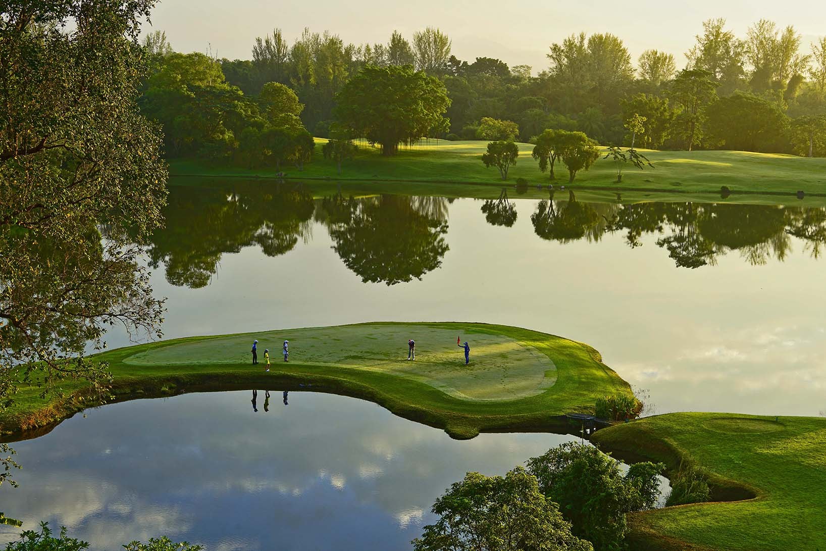 Island green reflected in a lake at sunrise, Pattaya, Thailand